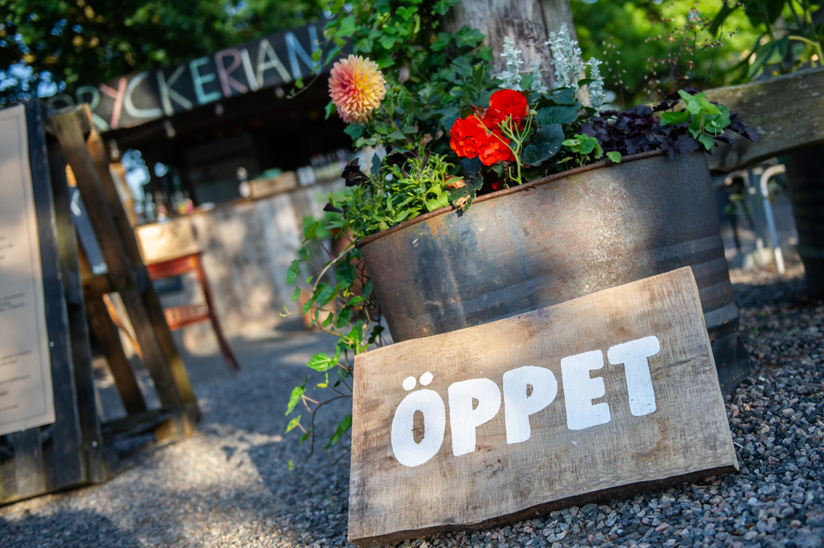 Öppetskylt på marken utanför en restaurang.