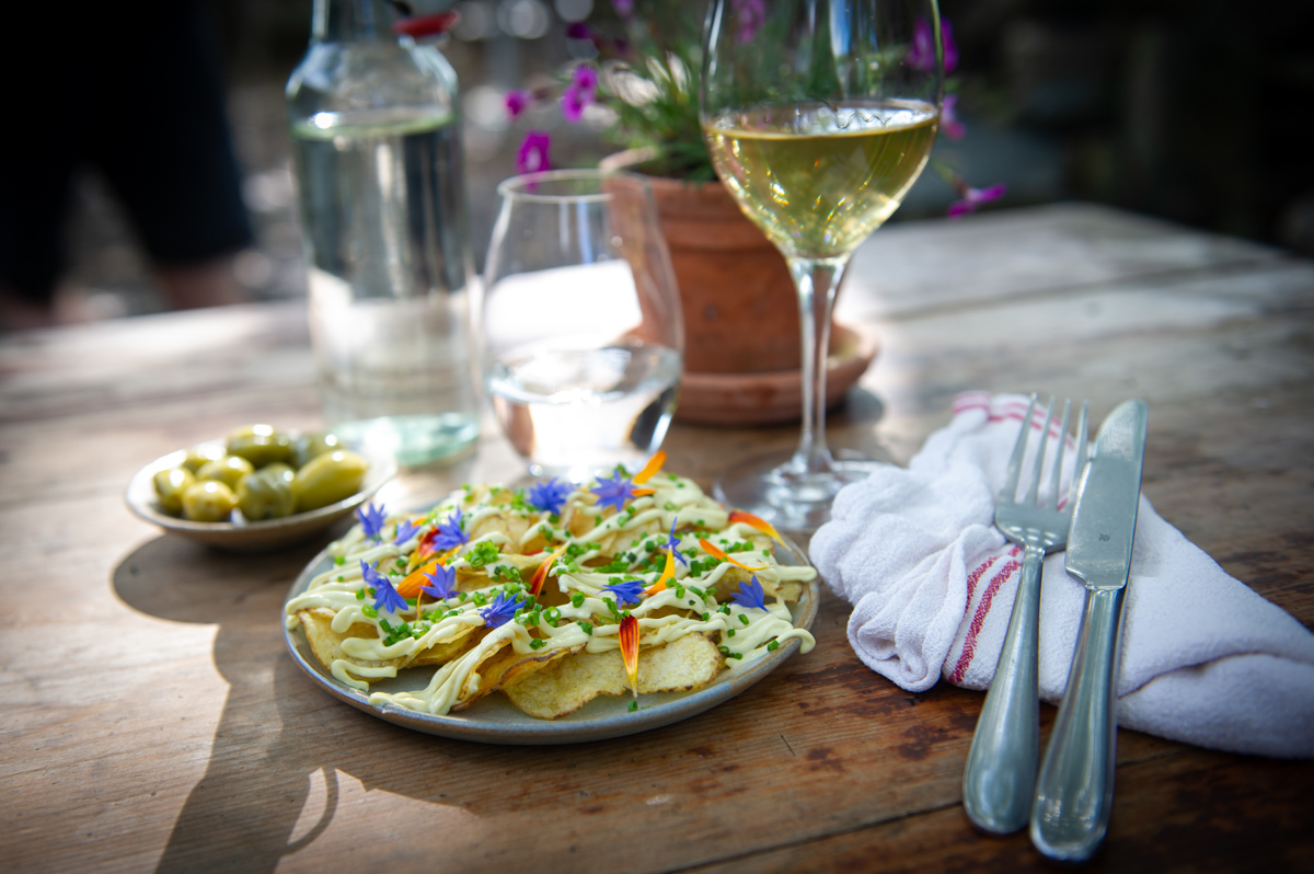 Förrätt serverad med vitt vin i motljus på ett träbord.