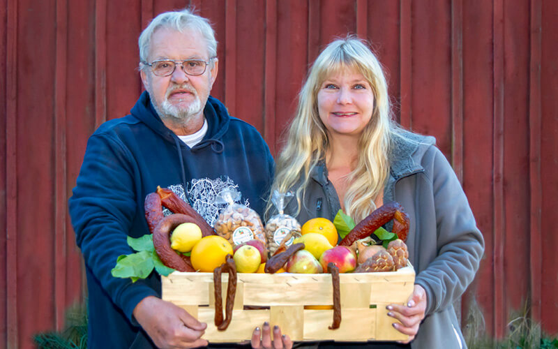 man och kvinna står och håller tillsammans i en spåmkorg med grönsaker och frukt.